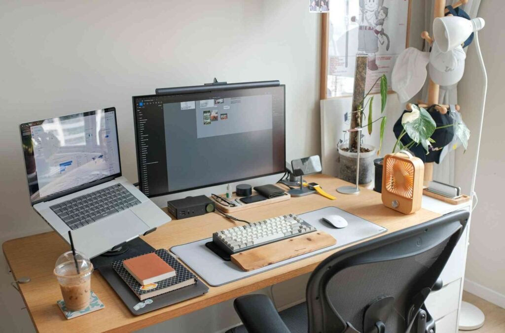 A desk with a laptop, monitor, keyboard and many more workspace items.