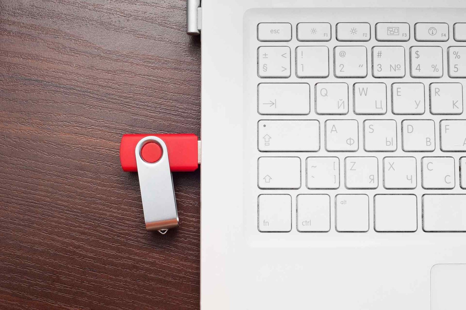 A red usb flash drive plugged into a white laptop.