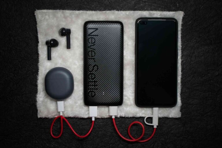A black powerbank connected to an air pod charger and a smartphone.