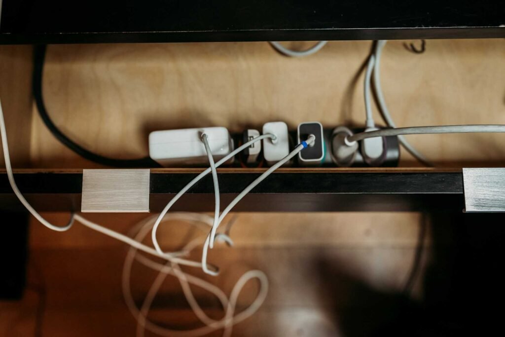 Multiple devices plugged into a power socket on a wooden floor.