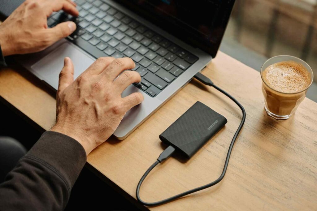 An ssd connected to a laptop being used by someone.