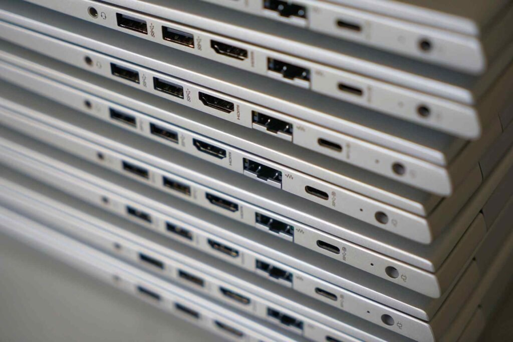 A stack of silver laptops from their side with USB C ports.
