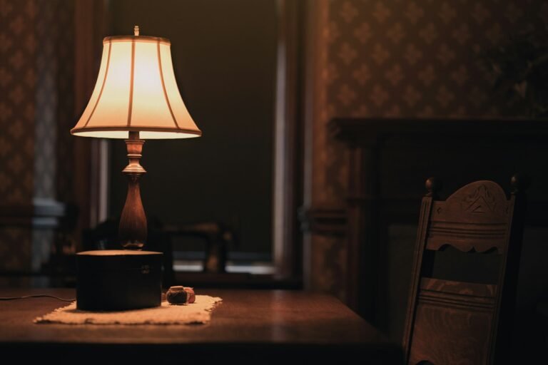 A table lamp on a wooden table next to a chair.