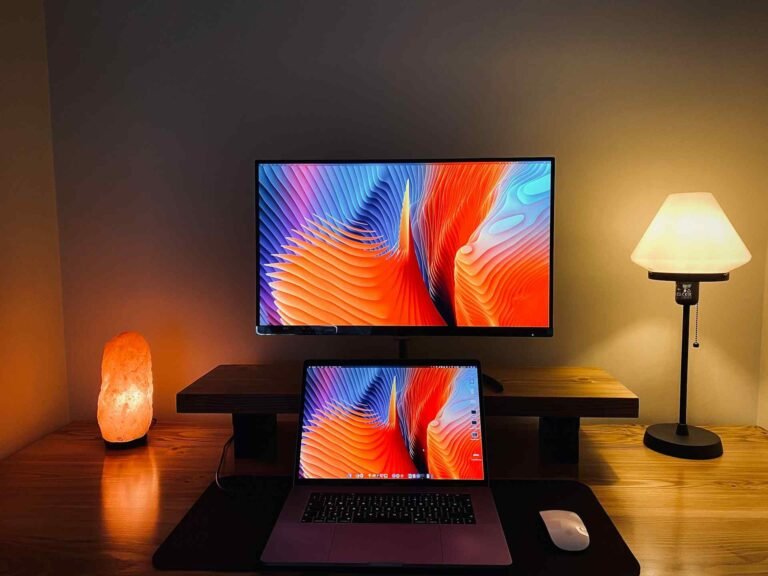 A warm lava lamp light and a slightly cooler lamp light at a workspace with 2 monitors behind each other.