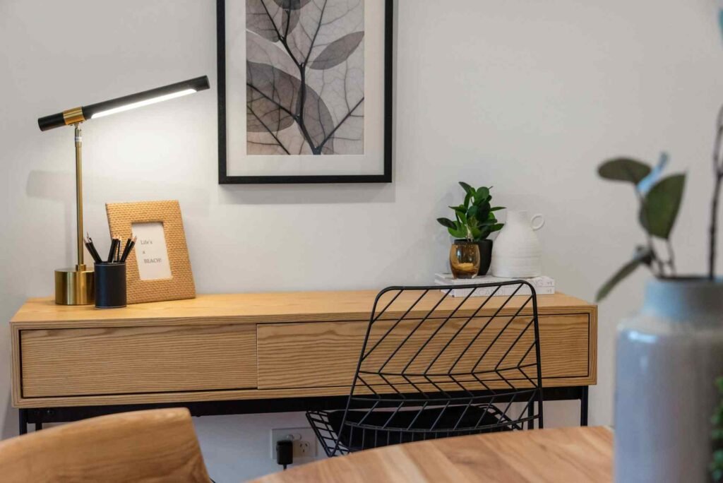 A bright metal desk lamp on a wooden reading table.