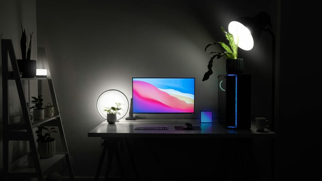 A flat screen with 2 bright white lights next to it and a keyboard and mouse in front.