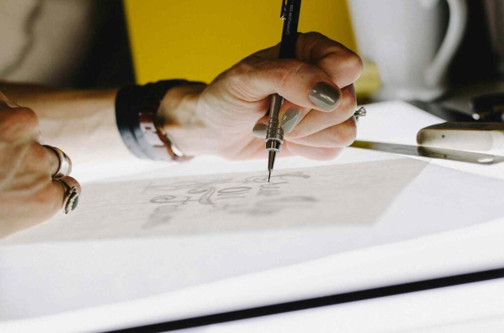 A person lettering on paper on top of a bright light.