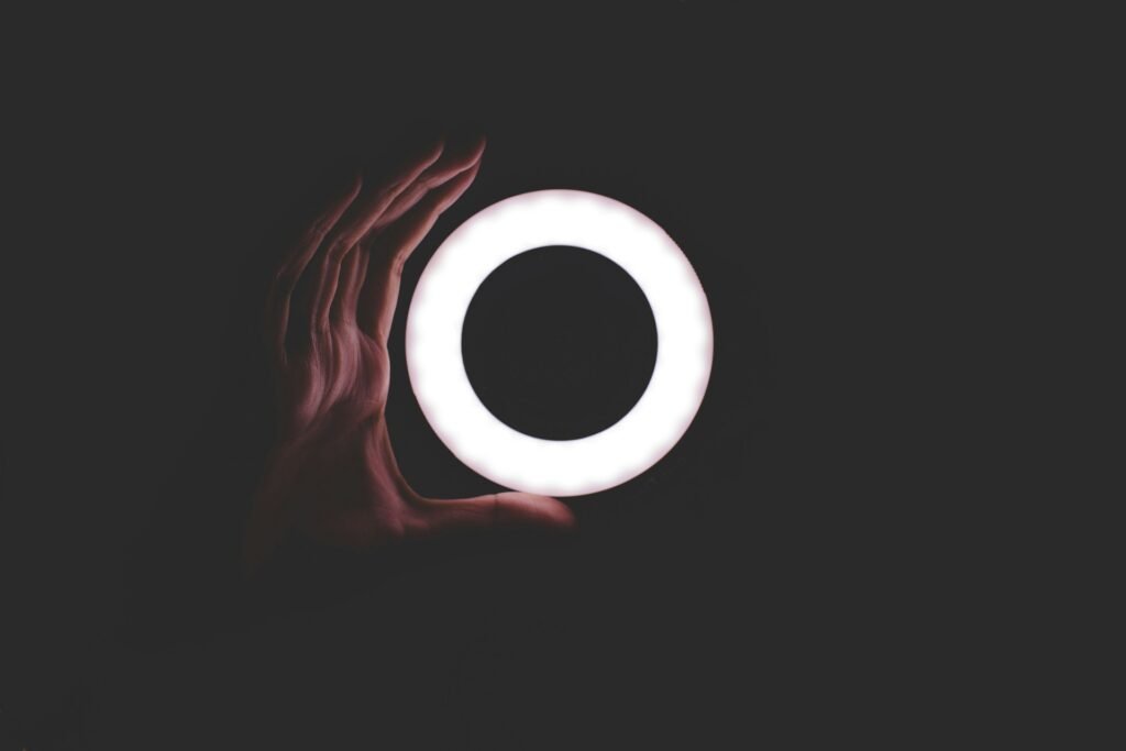 A white round clean led light with someone holding a hand next to it.