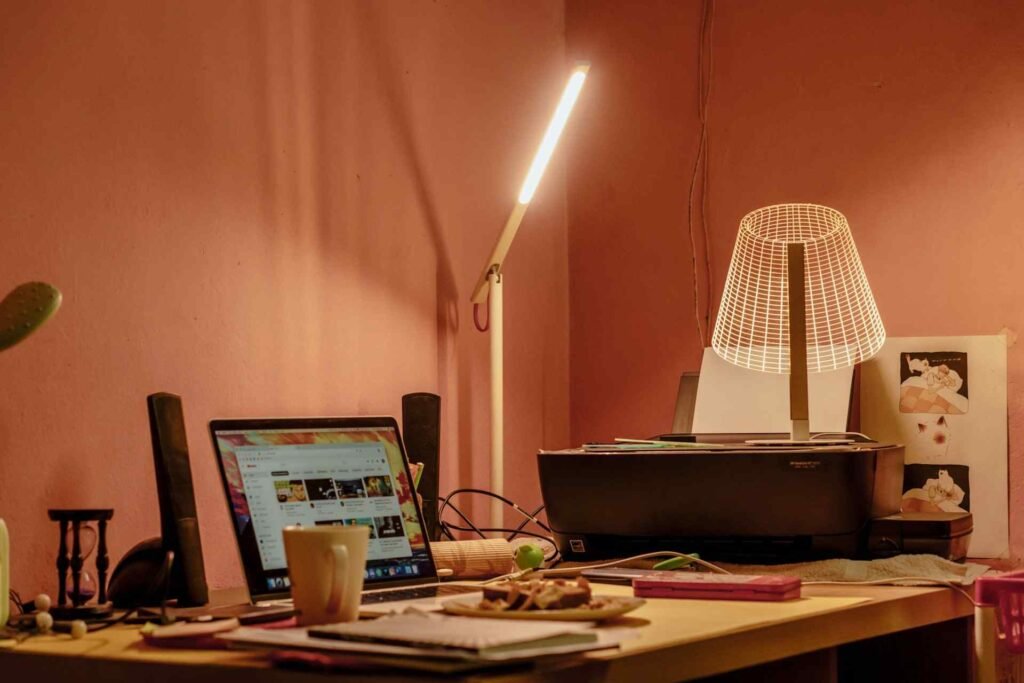 A white table lamp on a wooden work desk at home.