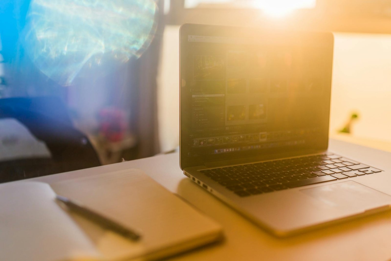 A laptop on a sunlit desk with a glare in the camera.