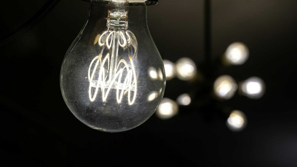 A LED light bulb in dark with some lights behind.