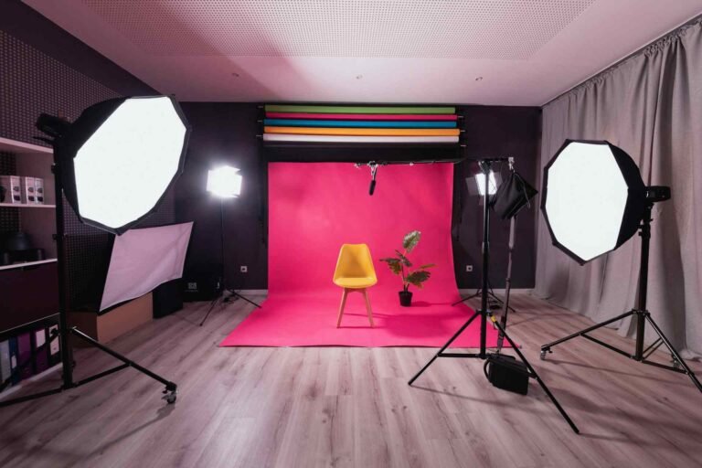 Multiple softboxes lighting a room with a red rug and a chair in the middle.