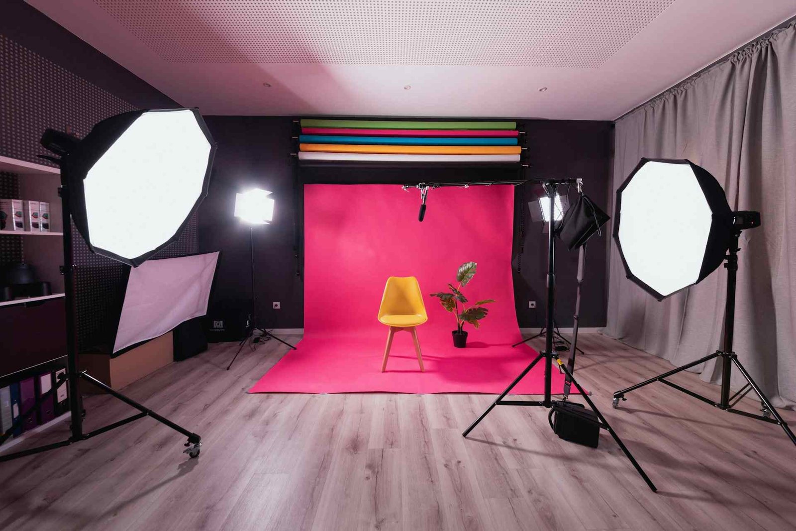 Multiple softboxes lighting a room with a red rug and a chair in the middle.