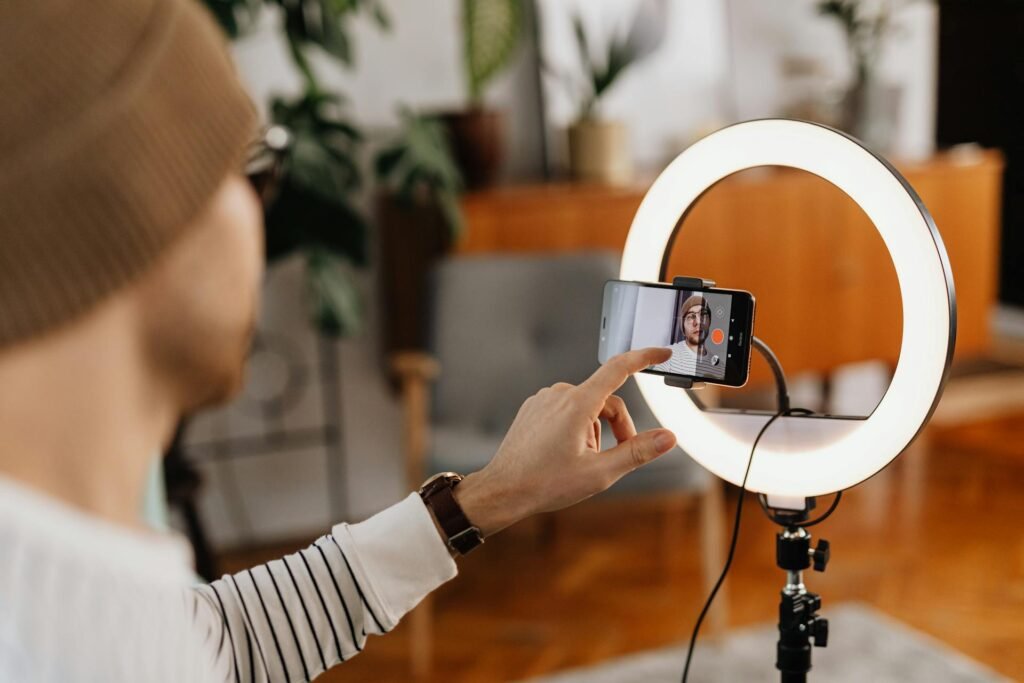 A person tapping on a smartphone in the middle of a ring light in a cozy room.