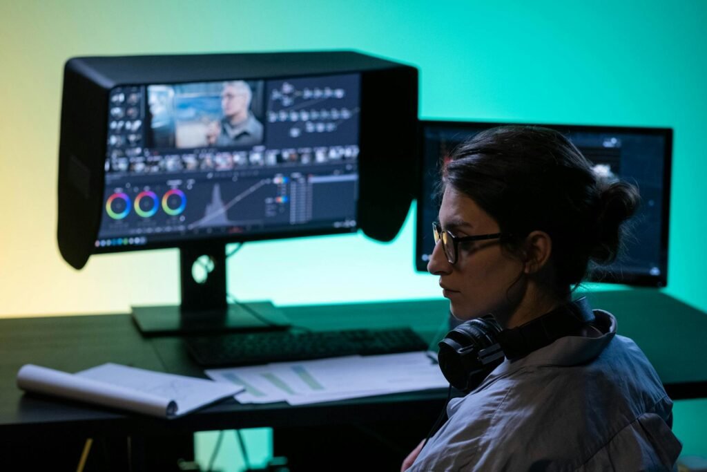 A women with headphones in front of a monitor with a hood.