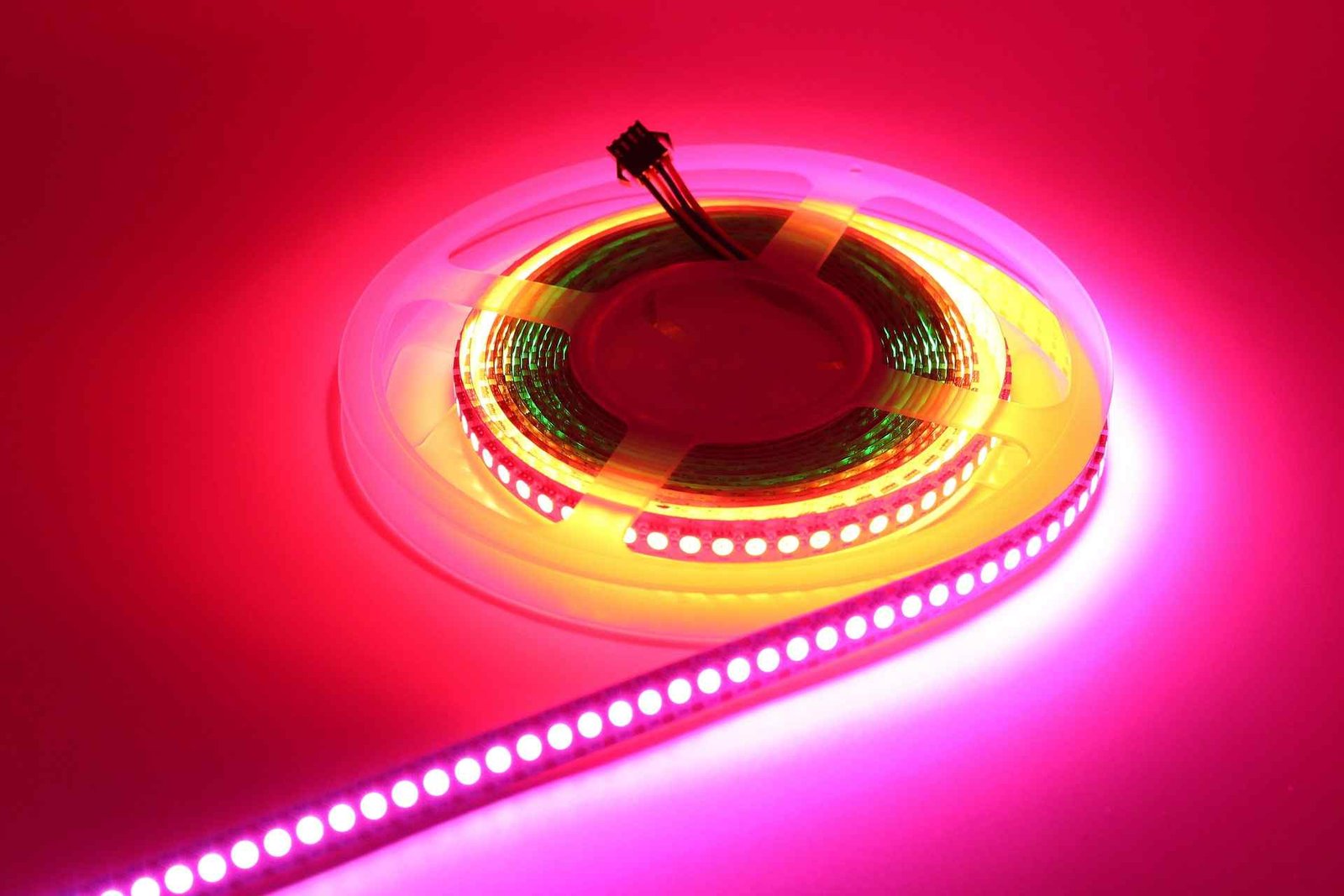 A long pink and red rgb LED strip light getting rolled out.