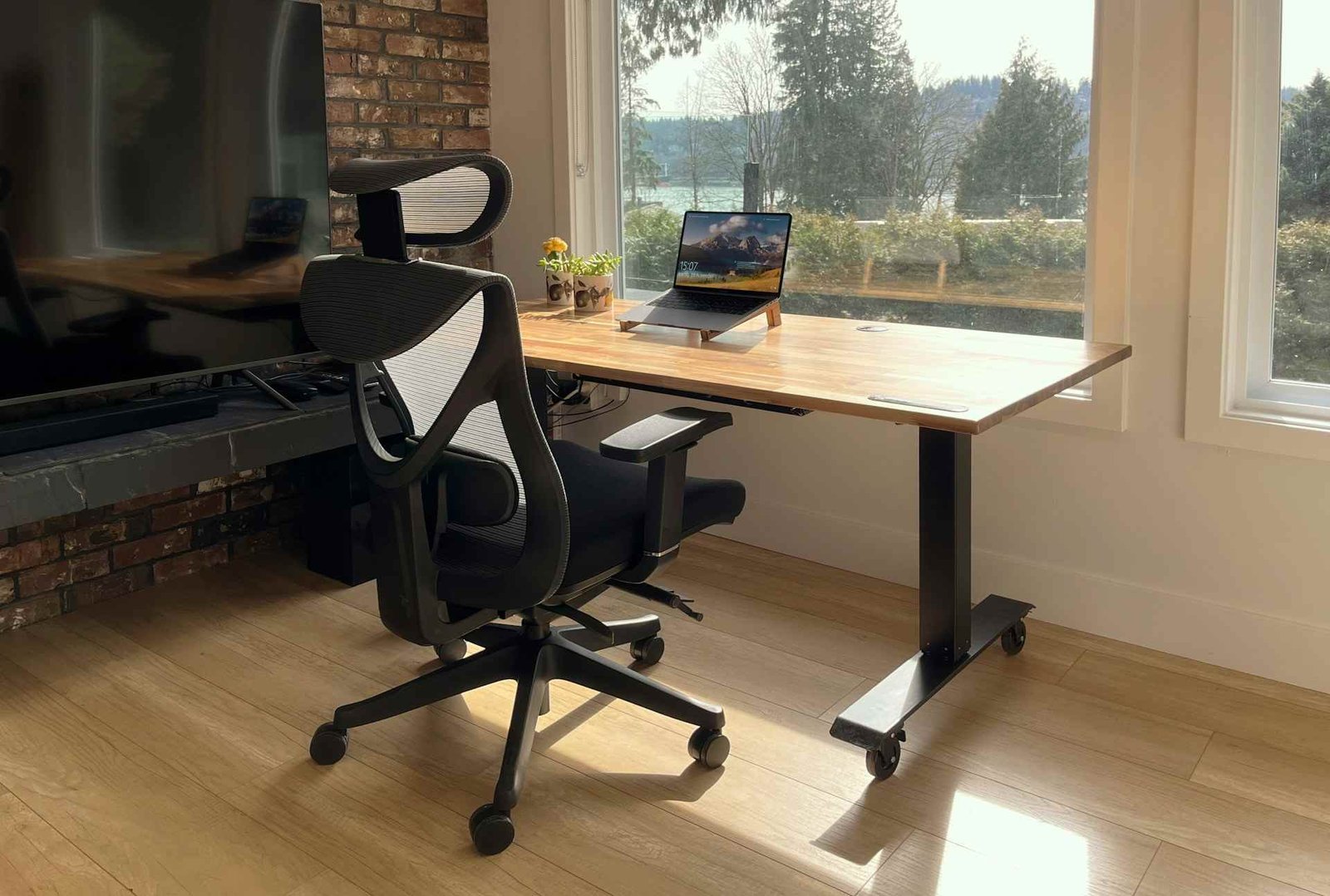 An image of an office setup with an ergonomic chair, a laptop and a height adjustable desk.