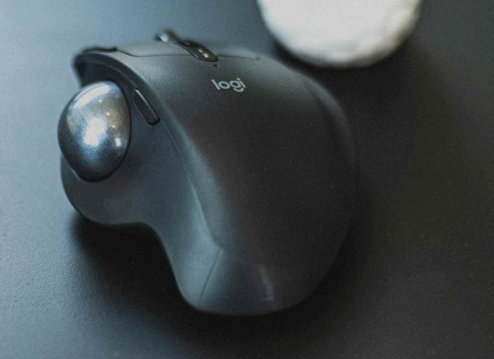 A logitech trackball mouse on a black table.