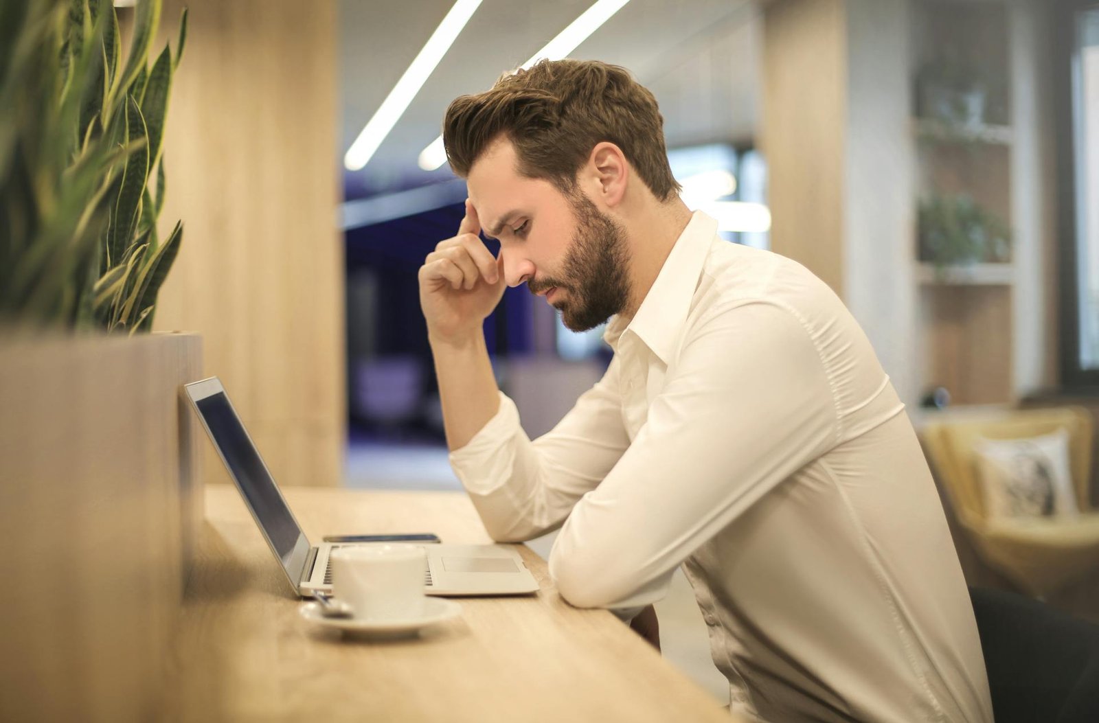 A person sitting in front of a laptop having headaches with LED lights around.