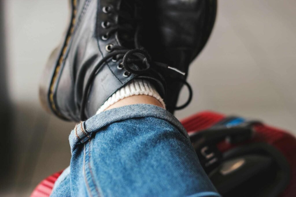 A person with their feet up wearing a pair of black shoes and jeans.