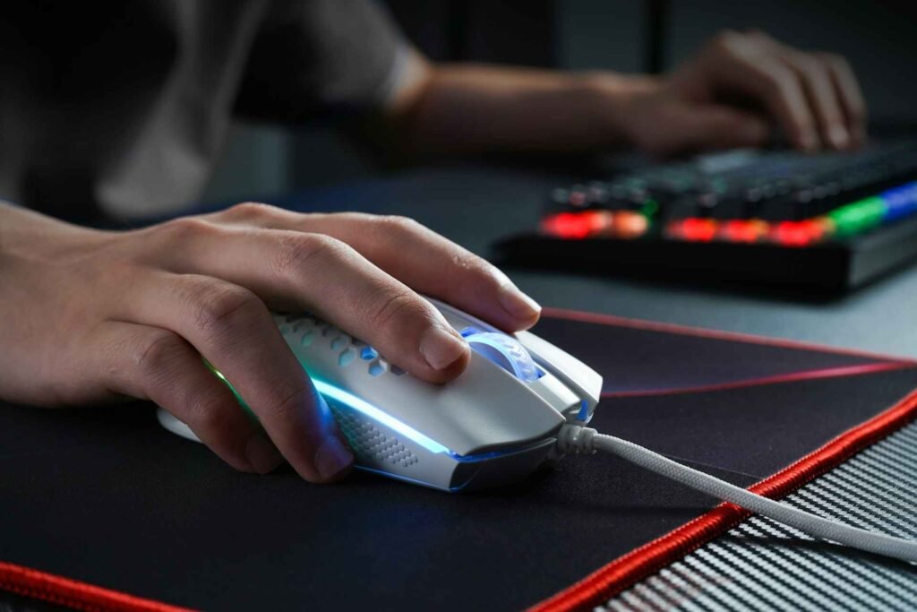A person playing with a wired white mouse on a mousepad with a red rim.