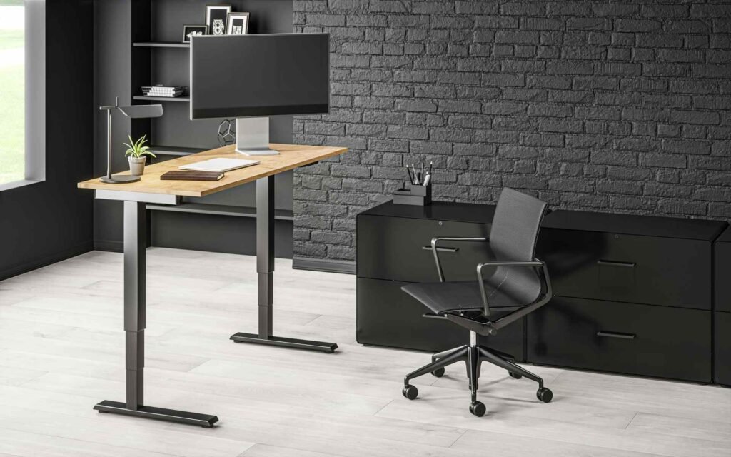 A wooden standing desk setup with a black monitor and ergonomic chair.