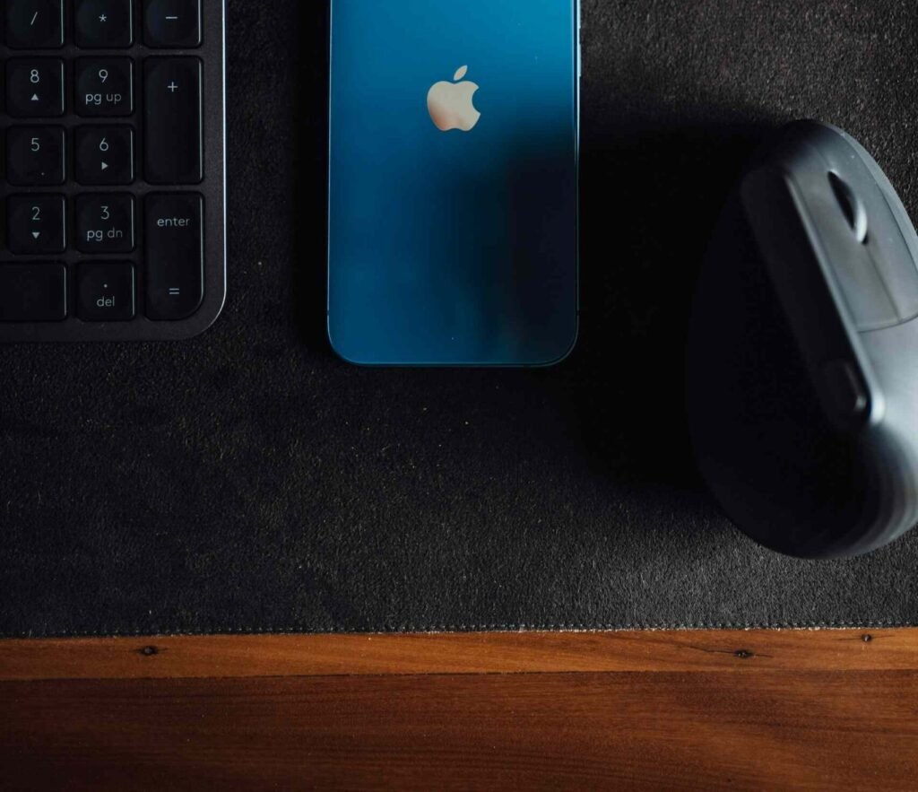 A vertical mouse on a mouse pad next to a blue phone and a keyboard.