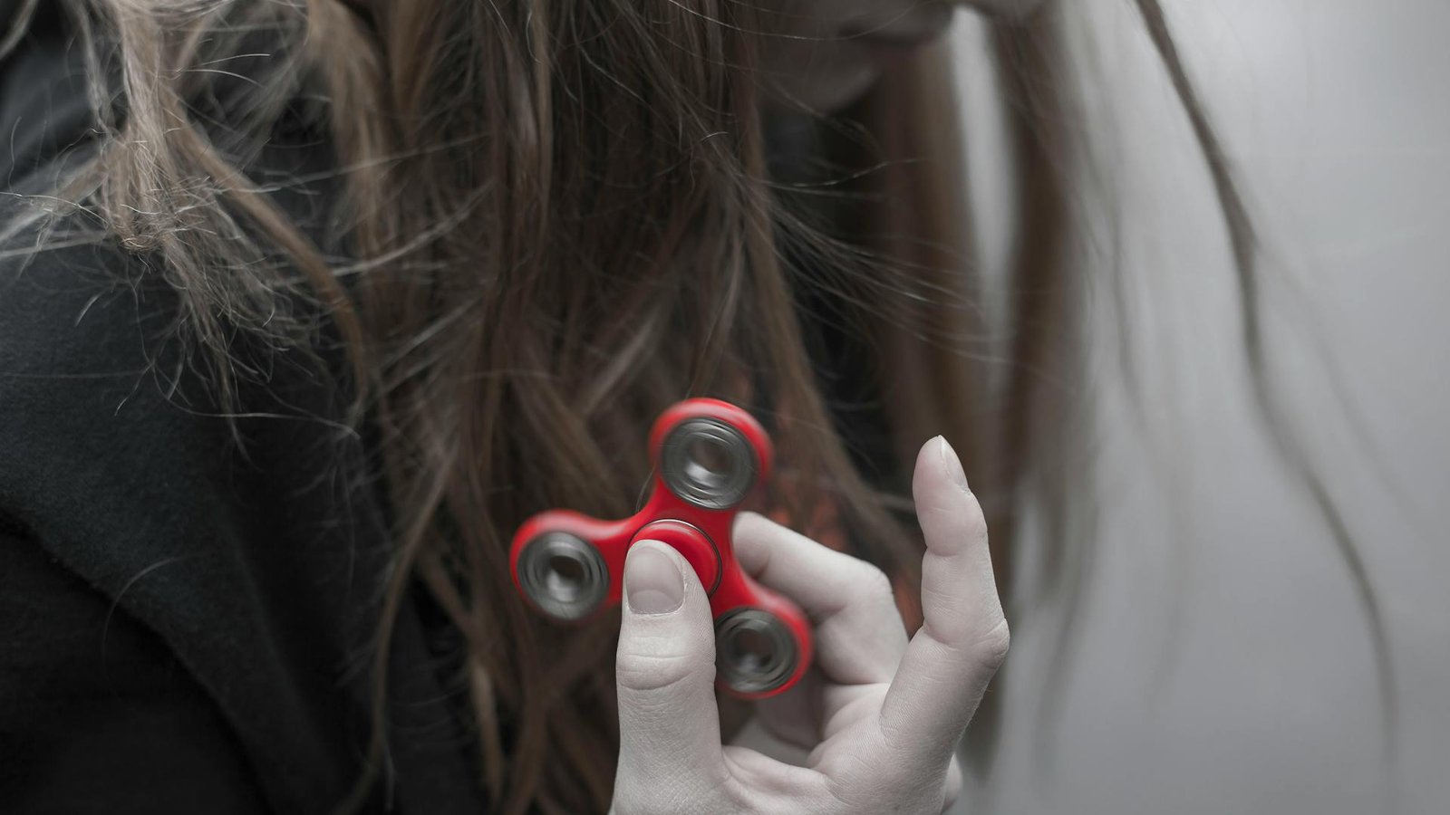 A women holding a red fidget spinner close to her hair.