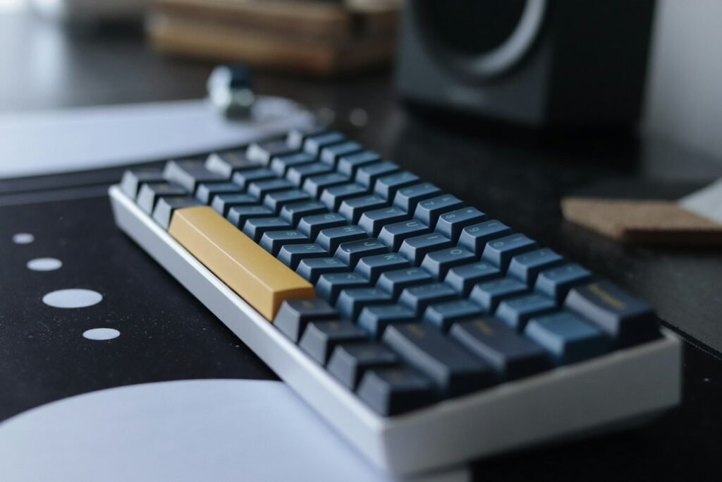 A blue, black, white and orange mechanical keyboard on a desk with a desk mat.