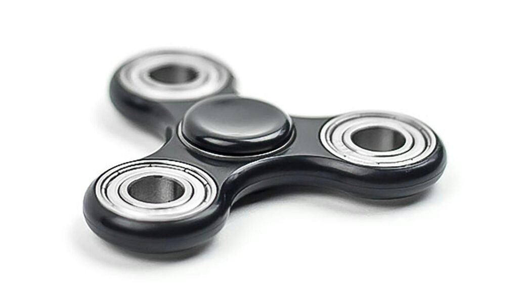 A black fidget spinner lying on a white surface.