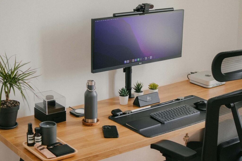 A clean home office desk setup with a monitor, ergonomic chair, adjustable table and lots of productivity tools.