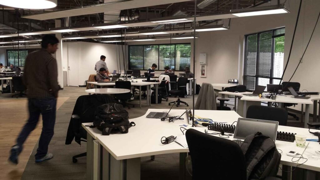 Multiple people working in and walking around an open office.