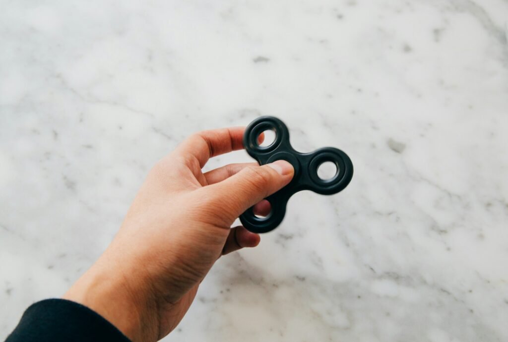 A person holding a black fidget spinner over a granite surface.