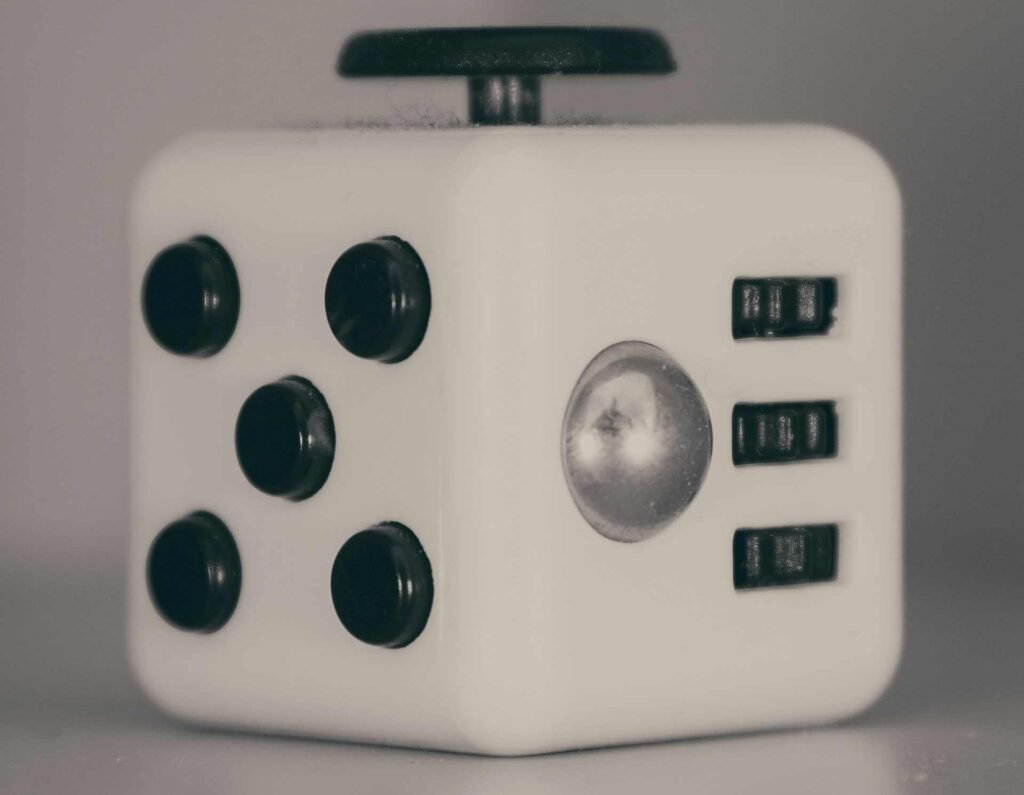 A close up of a white fidget cube with black buttons and surfaces around it.