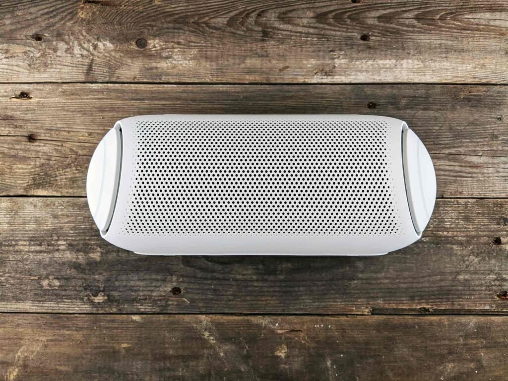 A white and long speaker on a wooden table.