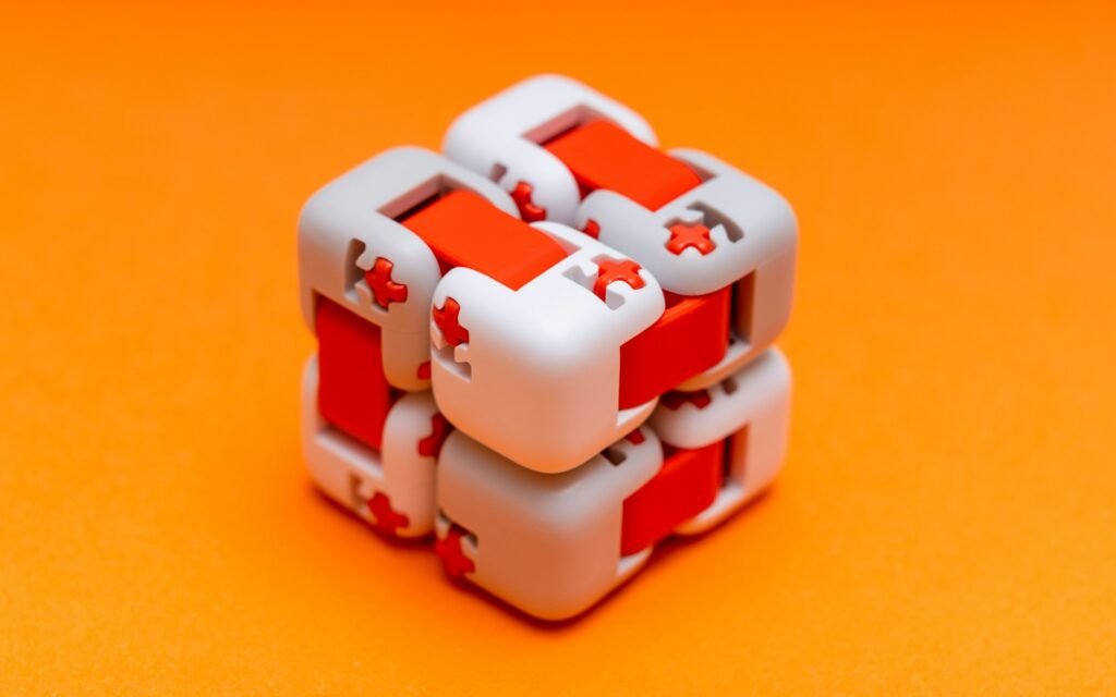 A white and red infinity fidget cube on an orange background.