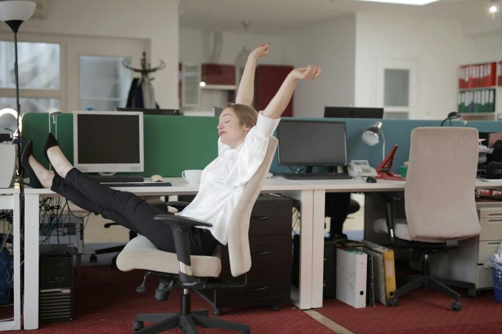 A woman stretching in an office chair at work.