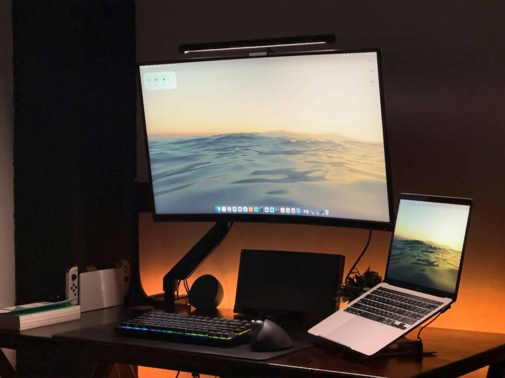 A curved monitor on a desk mount with orange backlight.