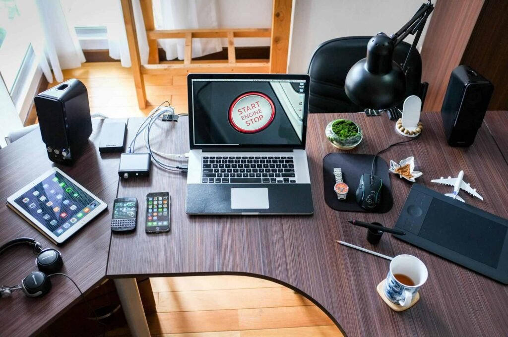 A wooden curved office desk with a laptop and multiple phones on it.