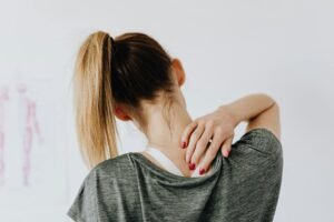 A woman with back pain touching her back.