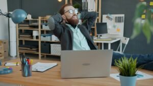 A man relaxing and leaning back in an office chair with his feet on the desk.
