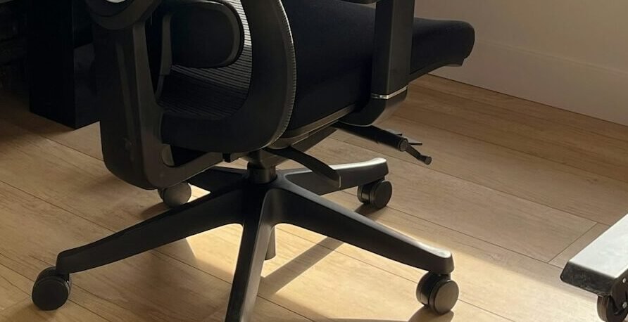 An office chair with tilt and adjustment levers on a wooden floor.