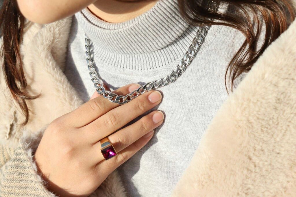 A woman with a turtleneck shirt, necklace and coat.