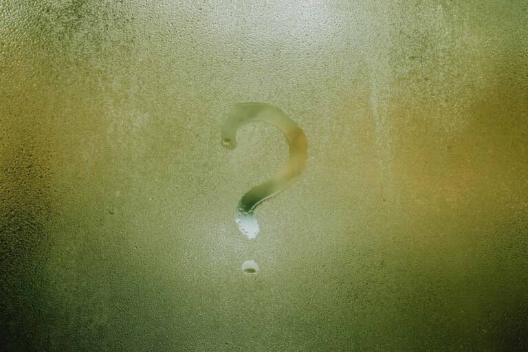 A glass surface with condensation water and a question mark written on it.