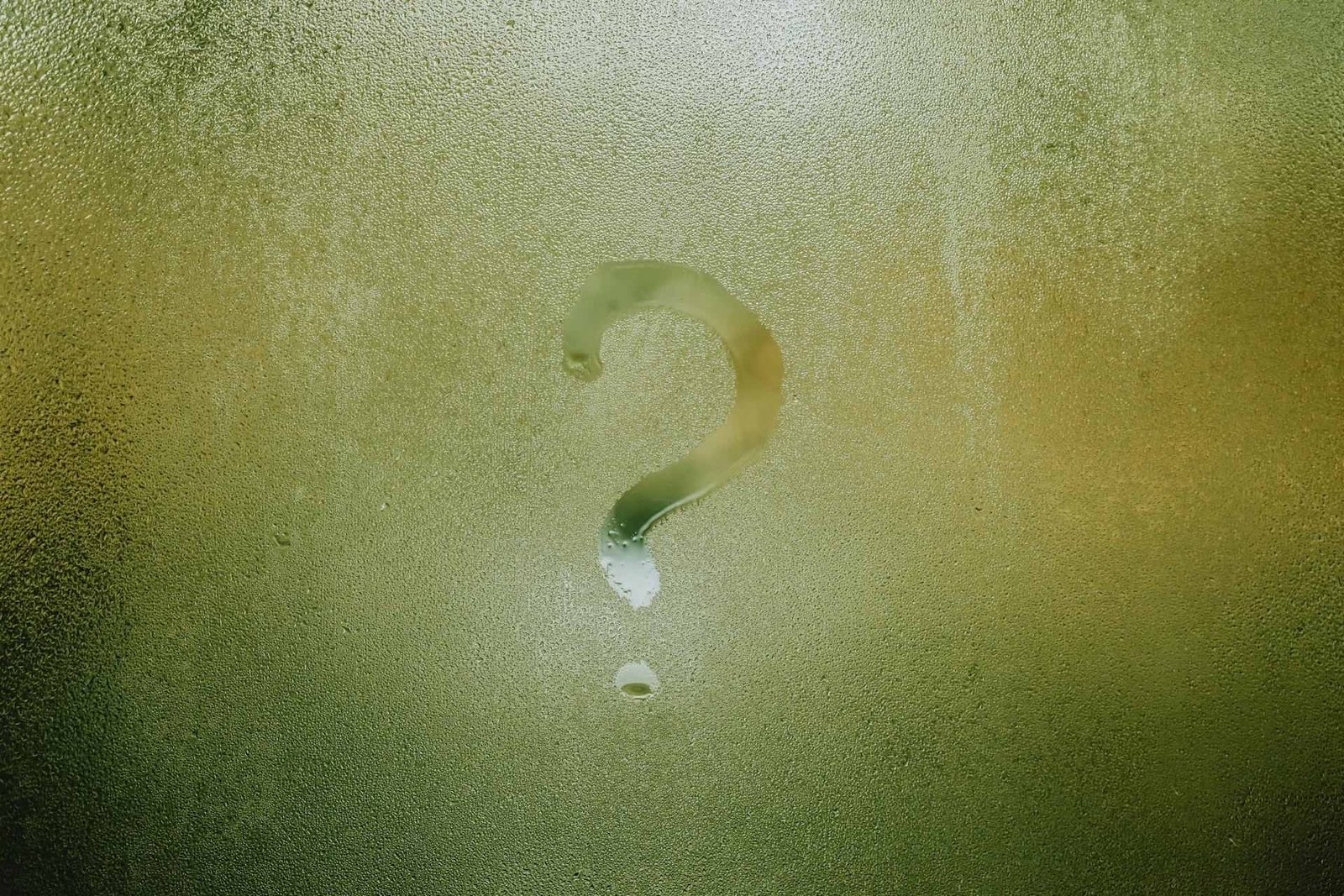 A glass surface with condensation water and a question mark written on it.