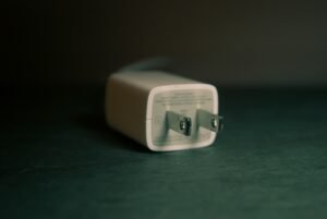 A white american plug lying on a green surface.