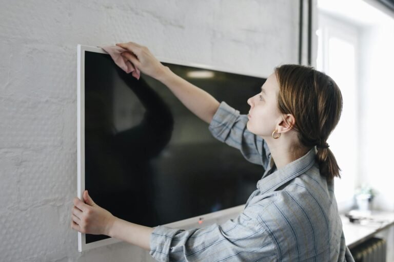 A woman cleaning a tv screen with some cloth.