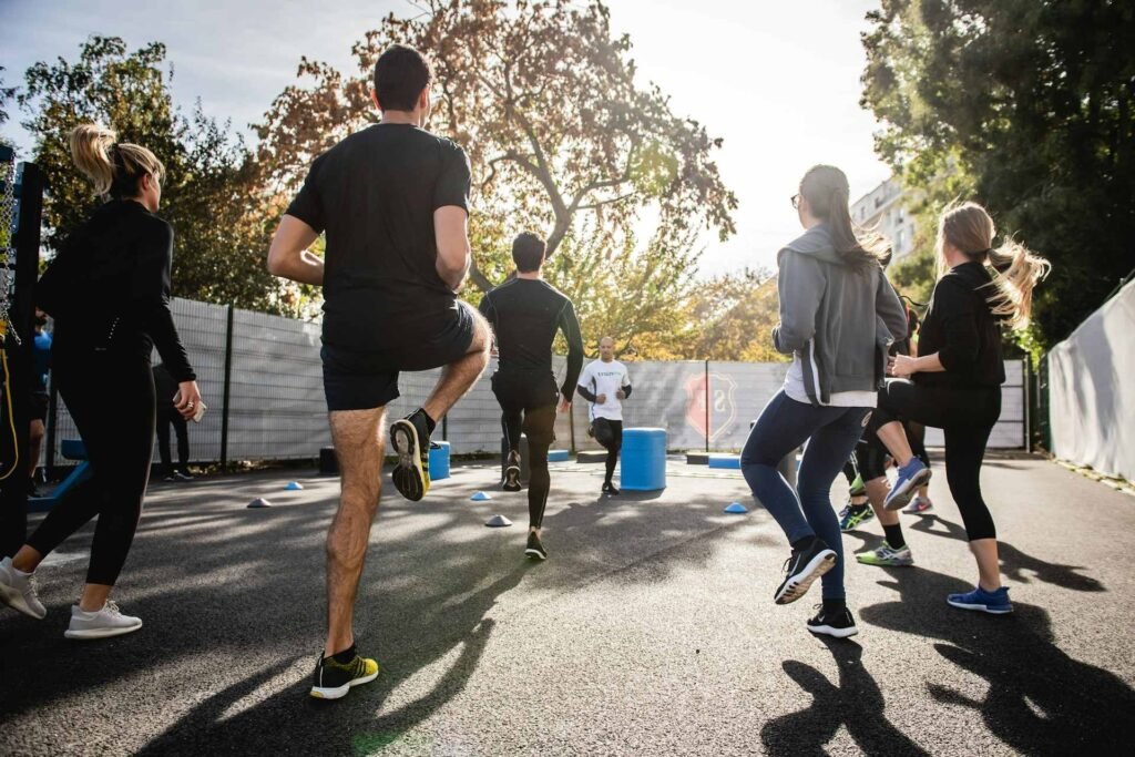 Multiple people doing fitness exercises outdoors on a sunny day.