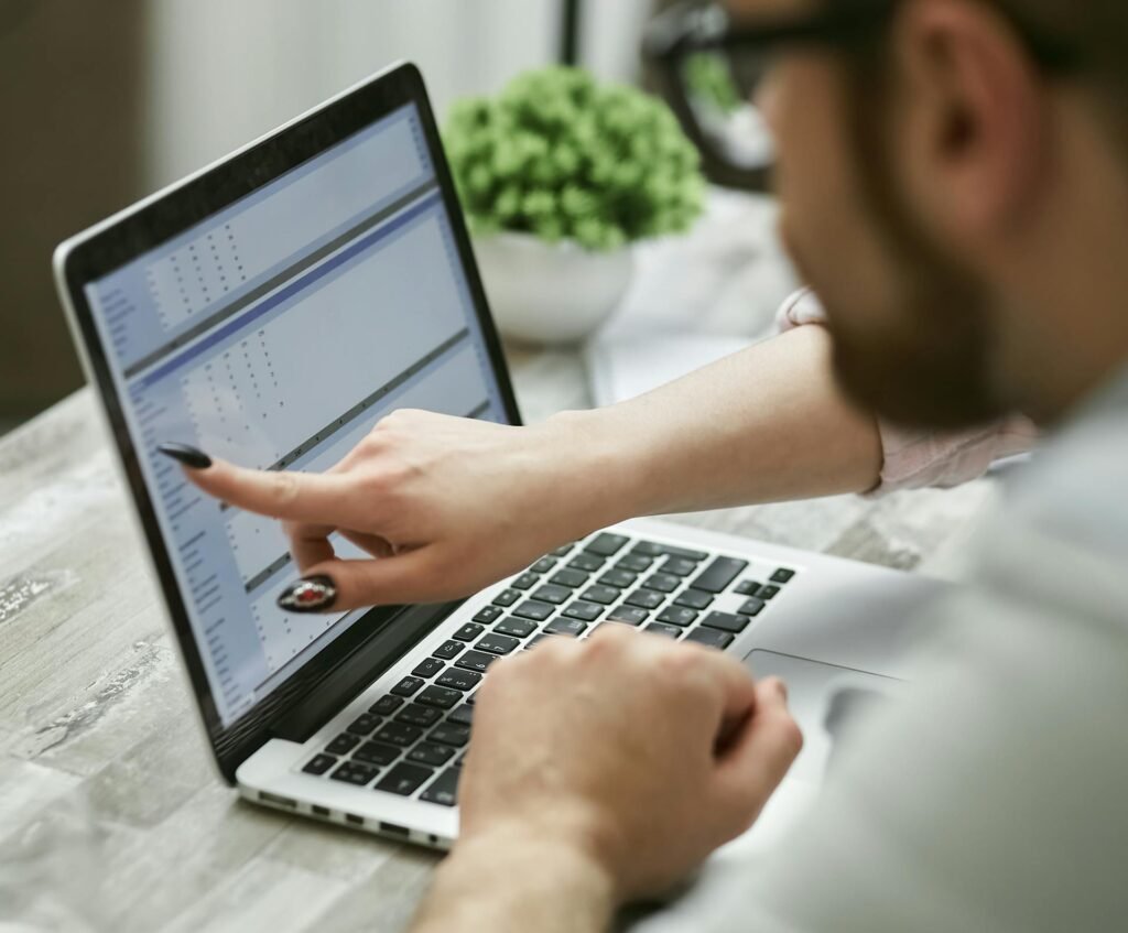 A woman with long nails touching a laptop screen.