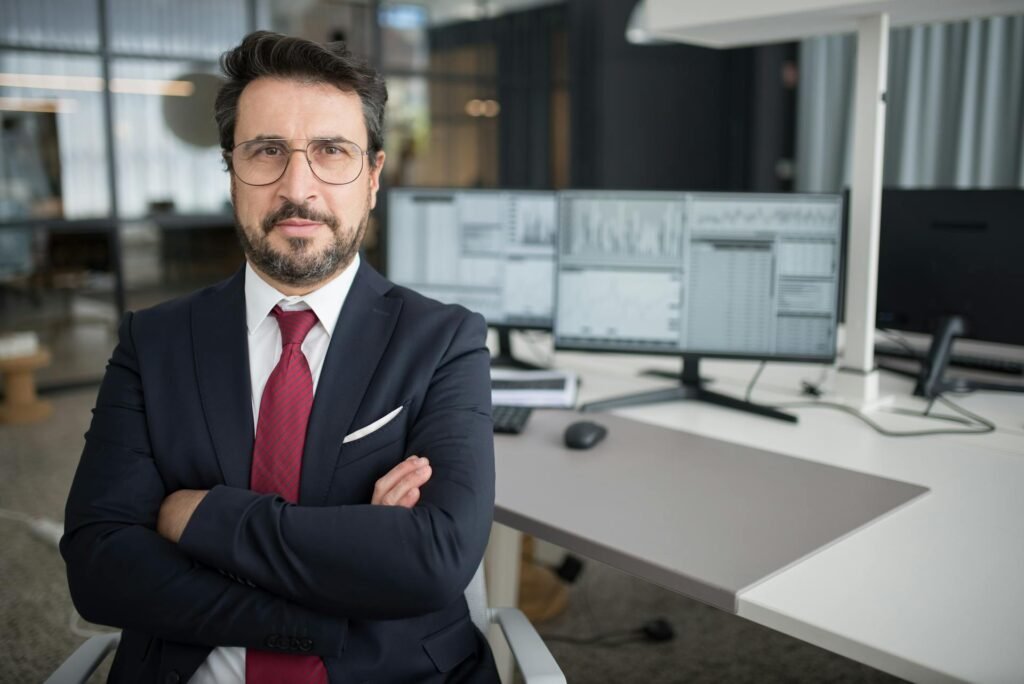 A business man with crossed arms in front of a work space.